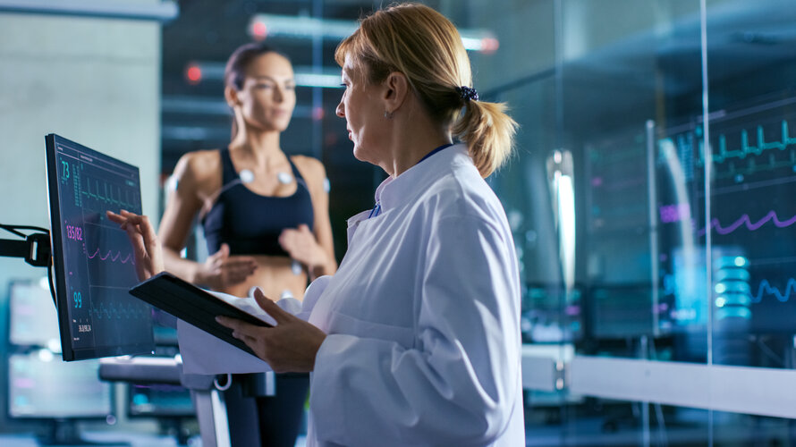 Ärztin steht am Monitor und Patientin ist auf einem Laufband für ein Langzeit EKG Ärztin steht am Monitor und Patientin ist auf einem Laufband für ein Langzeit EKG